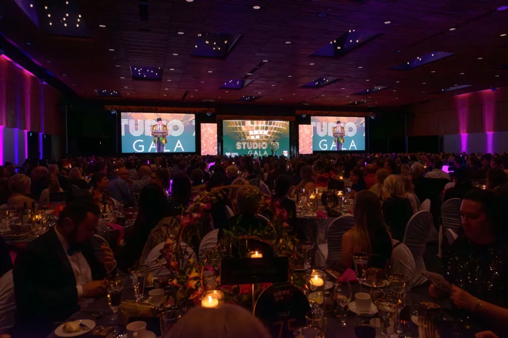 Attendees watching a presenter onstage during the Rainbow Resource Centre Gala