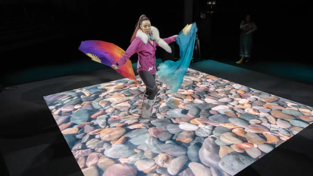 A woman dancing on a touch screen LED stage displaying pebbles in water