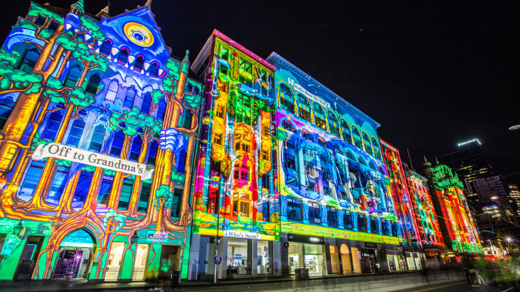 Projection mapping example of colors projected onto buildings.